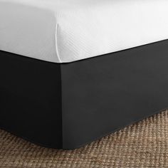 a black and white bed skirt on the bottom of a bed in a room with wicker flooring