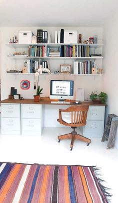 a room with a desk, bookshelf and rug