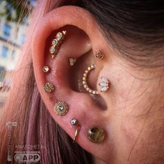 a woman with pink hair wearing several different ear piercings on her left side of the ear