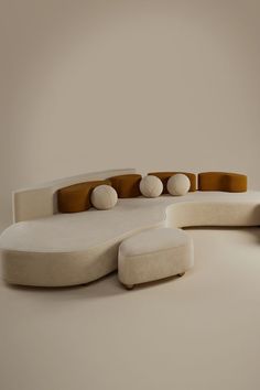 a white couch sitting on top of a floor next to a chair and ottoman in front of a wall