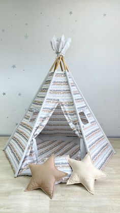 a teepee tent with three stars on the floor next to it and two pillows