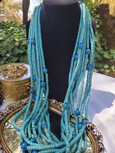 Multi Strand (9) Bead Boho Necklace with larger round wood beads. Color is a turquoise/ aqua (which ever your eyes see) Vintage from the 1980s This necklace is a charming funky necklace with some fancy charm. It could be worn during any season or just about any occasion and with any outfit, including jeans. Approx 15 inches long when hooked https://www.etsy.com/shop/VintageByTerri Please remember that these items are previously loved items...which is part of their charm. They all have their own Blue Wooden Beads For Festival, Unique Blue Wooden Beads, Traditional Turquoise Wooden Beads, Blue Wooden Beads, Blue Wooden Beads Festival Jewelry, Blue Wooden Beads Jewelry For Festival, Unique Blue Wooden Beaded Necklaces, Bohemian Turquoise Beaded Necklaces With Wooden Beads, Vintage Wooden Beaded Necklaces For Beach