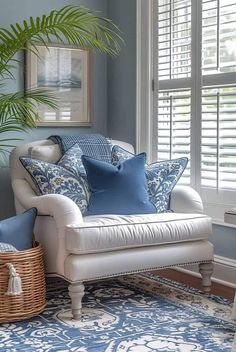 a blue and white living room with a couch, chair, rug and potted plant