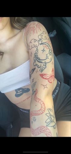 a woman with tattoos on her arm sitting in a car