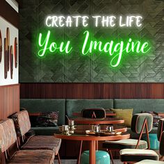 a neon sign that says create the life you imagine on it's wall above two tables