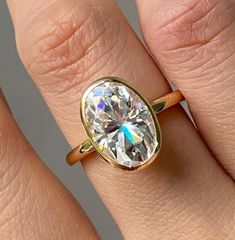 a woman's hand with a yellow gold ring and a white diamond in it