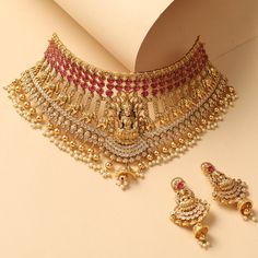 Description A cascading choker fit for a bride, this intricate choker neckpiece is the definition of regalia and opulence, studded with fine CZ and semi-precious Kempu stones. A head-turner, this gold plated nakshi temple choker features a parade of elephants centered with Goddess Lakshmi motif. Gold drop beads add royal charm to this necklace. Details & Specifications: Materials used: Brass Alloy with Antique Gold Plating Weight – Choker 135.62 gm, Earrings 24.16 gm Length – Choker 19 cm, Earri Wedding Necklaces For Bride Gold, Latest Gold Choker Necklace Designs, Choker Necklace Designs Gold Indian, Gold Necklace Set Bridal, Gold Choker Necklace Indian, Gold Choker Necklace Set, Choker Sets, Wedding Jewellery Designs, Bridal Jewelry Sets Brides