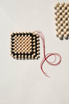 two pieces of beaded art sitting next to each other on a white table top