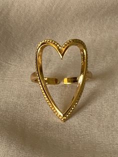 Fall head over heels for this golden Heart Outline Ring! Crafted from Gold Filled material, this statement piece will always keep your love at the forefront of your look. Elevate your every day style with the sweetest ring you'll ever see! Product Details Material: Gold Filled Size: Adjustable Sweet Ring, Heart Outline, Golden Heart, Head Over Heels, Statement Pieces, Heart Ring, Gold Filled, Gold Bracelet, Every Day