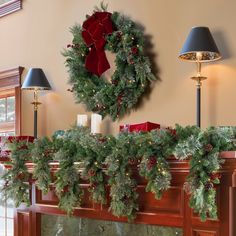 a mantle decorated for christmas with wreaths and candles