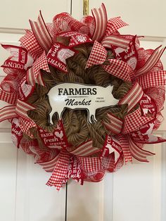 a red and white wreath that says farmers market hangs on the front door with a cow