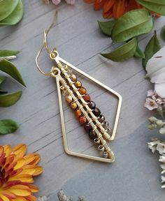 These lightweight earrings are a fun and easy way to add a pop of color and bit of bold, geometric design to your everyday look!  They feature satin gold, asymmetrical triangles wrapped with a gradient of light & dark gold, brass, orange, antique copper, red, bronze, and brown glass beads. The earrings measure just over 2" long x .625" wide. The earwires are 10kt Gold-Filled and are 100% nickel-free. Please note:  each pair of earrings is made to order and there may be slight variations from piece to piece.  Please allow 3-7 days for creation before this item is ready to ship. Thanks for checking out the shop and feel free to drop me a line if you have any questions! Bar Stud Earrings, Bracelets Diy, Red Boho, Copper Red, Triangle Earrings, Diy Schmuck, Wire Earrings, Jewelry Projects, Etsy Handmade