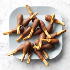 chocolate covered pretzels are arranged on a white platter with yellow sticks sticking out of them