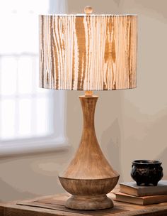 a wooden table with a lamp on top of it next to a book and vase