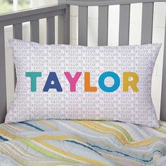 a pillow that says taylor on it in multicolored letters sitting on top of a bed