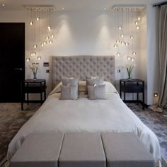 a large white bed sitting in a bedroom next to two night stands and lamps on the wall