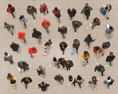 an overhead view of many people walking down the street, with one person holding a cell phone