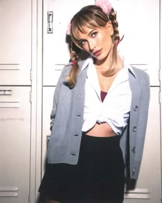 a young woman posing in front of lockers with her hands on her hips and looking at the camera