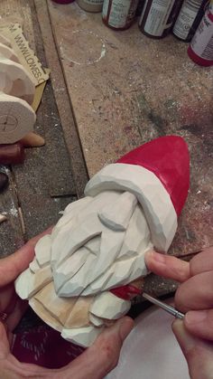 two hands are working on a piece of wood that has been carved into the shape of santa's hat