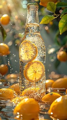 oranges falling into water in front of a glass bottle with lemon slices on it