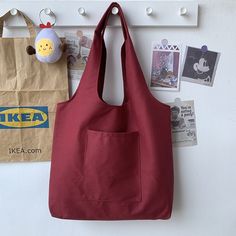 a red bag hanging on the wall next to a paper bag and a stuffed animal