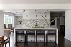 a kitchen with marble counter tops and stools next to an island in the middle