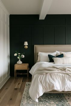 a bedroom with dark green walls and white bedding in the corner, along with a rug on the floor