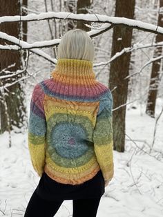 a woman standing in the snow wearing a colorful sweater