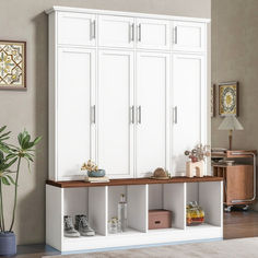 a room with white cabinets and shelves filled with items on the floor next to a potted plant