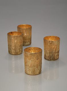 three gold colored glass candlesticks sitting on top of a table next to each other