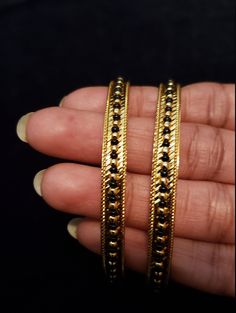 "* Handcrafted Gold Plated 2 Bangle Set. Sold as a set. * Bangles with prettY Black and gold color beads. * High Quality 22 K Gold Plated- 2 Bangle set * Size 2.6 has 2.40\" inner circle diameter; size 2.8 has 2.53\" inner circle diameter Gorgeous gold-plated bangle/ bracelet best exemplifies the careful craftsmanship done on it -- a specialty at Nemali Jewelry. It has a special tone of elegance attached to it. The intricate handmade design of the bangle/bracelet set gives it a fresh and origina Black Beads Bangles, Beads Bangles, Bangles Set, Bangle Bracelet Set, Color Beads, Bead Bangles, Inner Circle, Bangle Set, Handmade Design