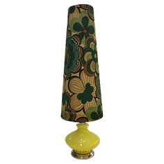 a yellow lamp with a green and brown flower design on the shade is sitting in front of a white background