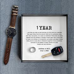 a watch and keys are sitting next to a card with the words 1 year written on it