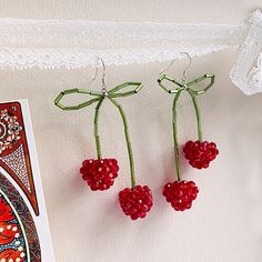 three cherries hanging from a string next to a card