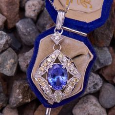 This pleasing 18k white gold pendant is centered with an oval cut tanzanite that weighs 3.57 carats, and is set in a four-prong setting. The tanzanite is surrounded by eighteen (18) bead set round brilliant cut diamonds, and one (1) bezel set pear brilliant cut diamond accent. The pendant is topped by a bead set round brilliant cut diamond and a 14k white gold bail. The pendant measures 41.5mm long, including the bail, by 20.7mm wide. It hangs on an 18-inch long, 1.0mm wide, 14k white gold cable Elegant Oval Tanzanite Gemstones, Exquisite Tanzanite White Gold Jewelry, White Gold Tanzanite Jewelry In Pear Shape, White Gold Tanzanite Oval Necklaces, Brilliant Cut Tanzanite Gemstones, Classic Tanzanite Multi-stone Jewelry, Elegant Tanzanite Oval Pendant Jewelry, Fine Tanzanite Oval Pendant Jewelry, Heirloom Tanzanite Gemstone Jewelry