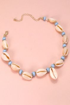 a necklace with seashells and blue beads on a pink background is shown in this image