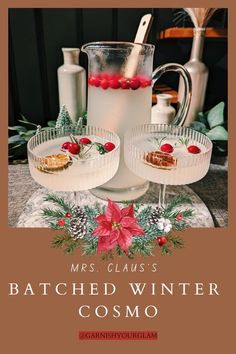 two glasses filled with liquid sitting on top of a table next to a pitcher and christmas decorations