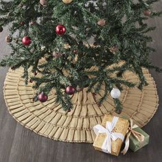 a christmas tree with presents under it on the floor next to a wicker mat