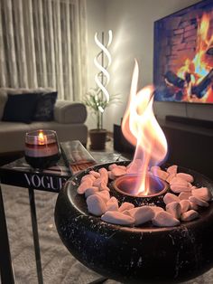 a living room with a fire pit in the center and candles on the table next to it