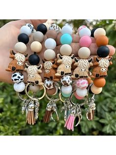 a hand holding a bunch of different key chains with animals on them and some beads hanging from it