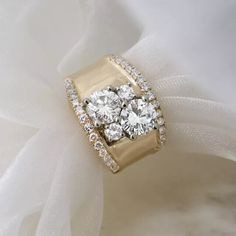 an engagement ring with three round diamonds on top and white tulle around the band