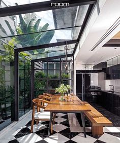 a dining room table and chairs in front of an open kitchen area with large windows