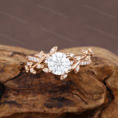 an engagement ring on top of a piece of wood with diamonds in the center and leaves around it