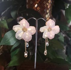 a pair of pink flowers with pearls hanging from them