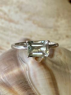 This classic East West solitaire setting contains a beautiful 2.00ct genuine prasiolite. The emerald cut stone measures approximately 8x6mm. The ring is available in sterling silver, and 14k white, yellow, or rose gold. This ring makes a great promise or engagement ring. Please send me a message if you need a size not listed. * This ring can be customized with any color center stone. All items are handmade by me in my shop in Woodbridge, NJ. Please message me with any questions. Shipping within Classic White Sapphire Gemstone Ring, Classic Emerald-cut Topaz Ring In Sterling Silver, Classic Emerald Cut Ring With Ethically Sourced Gemstones, Emerald Cut Sapphire Solitaire Promise Ring, Emerald Cut Solitaire Sapphire Promise Ring, 14k White Gold Emerald-cut Topaz Ring, Classic Emerald Cut Topaz Ring With Vs Clarity, Classic Emerald Cut Amethyst Ring, Classic White Sapphire Emerald Cut Ring