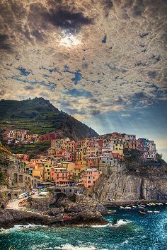 the sun is shining over an island with many houses on it and boats in the water