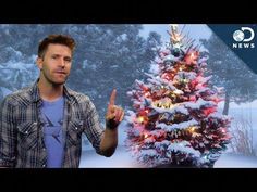 a man standing in front of a christmas tree giving the peace sign with his hand