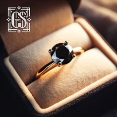 a black diamond ring sitting in a velvet box