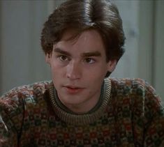 the young man is wearing a sweater and looking at something in front of his face