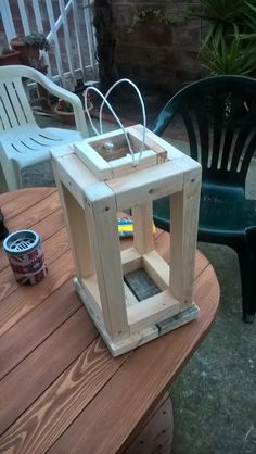 a small wooden lantern sitting on top of a table next to a green plastic chair